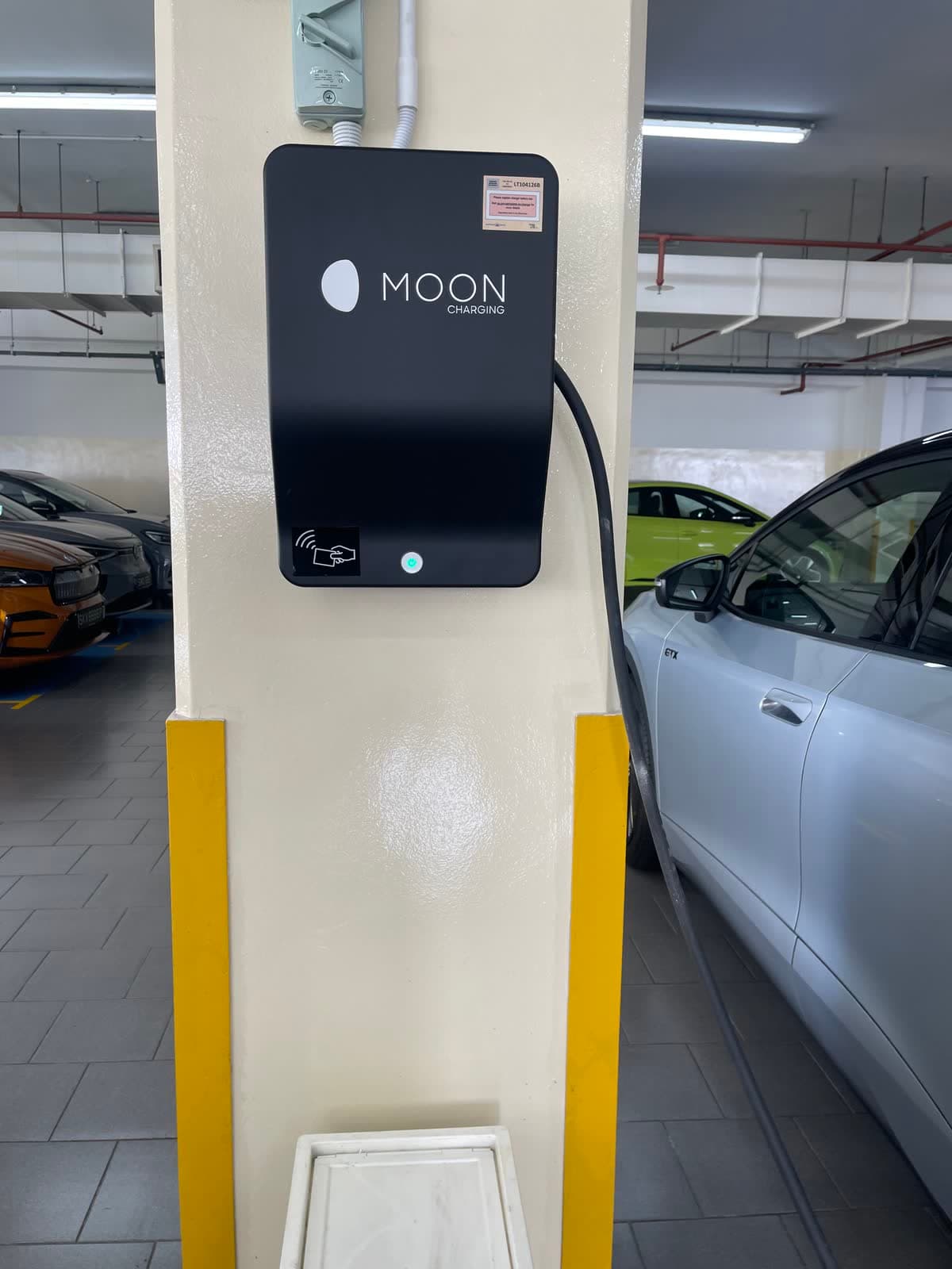 Wall-mounted AC charger with its LTA registration label on a car park pillar