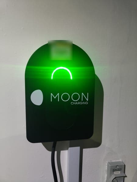 Moon Charging wallbox glowing green on a white wall