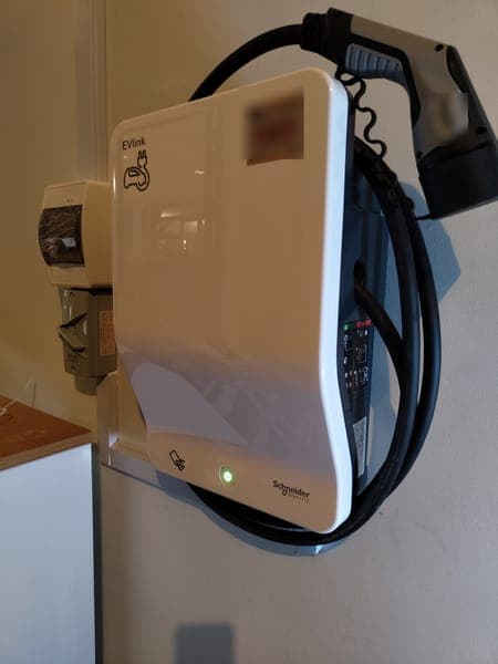 White Schneider EVlink wallbox with its cable and Type 2 plug hung on the side