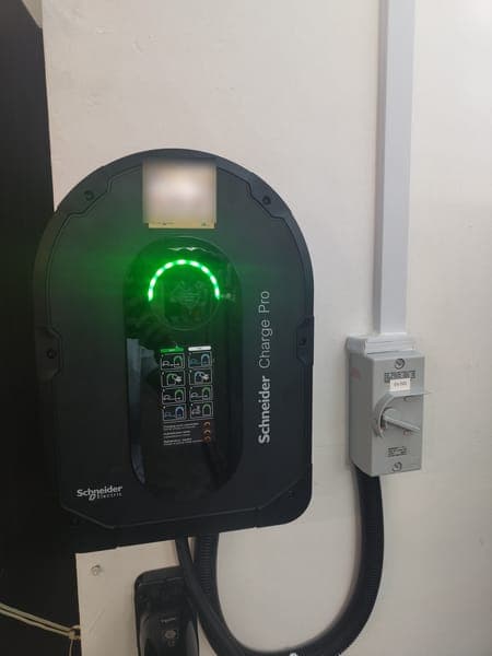 Black Schneider Charge Pro wallbox with a green ring light and isolator on a white wall