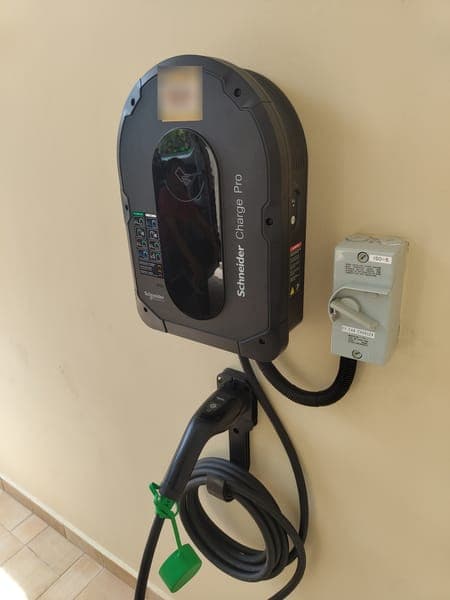 Schneider Charge Pro wallbox with a holstered Type 2 plug and isolator on a cream wall