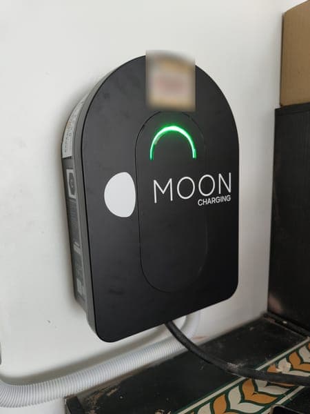 Moon Charging wallbox with a green light above a patterned tiled floor