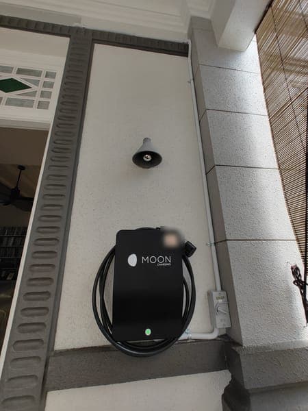 Moon Charging wallbox below a bell on the porch wall of a landed home