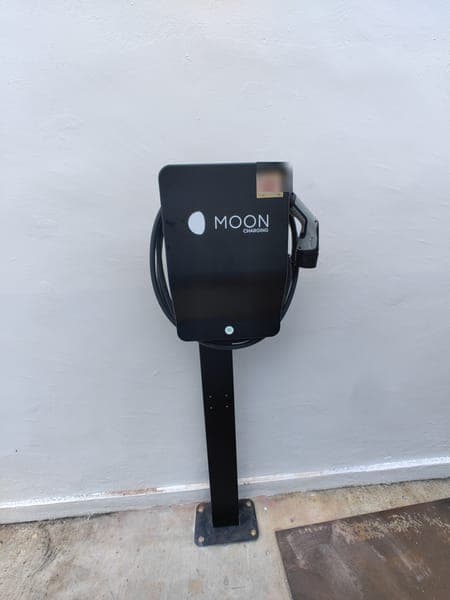 Moon Charging wallbox on a black pedestal on a driveway