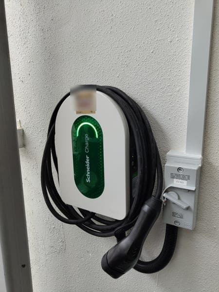 White Schneider Charge wallbox with its cable coiled around it and a Type 2 plug in front