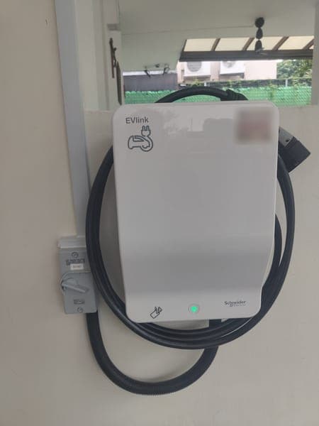 White Schneider EVlink wallbox with a coiled cable in a covered car porch