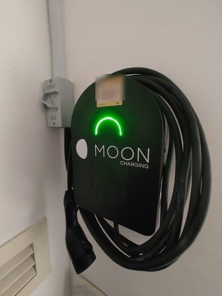 Moon Charging wallbox with a green light and coiled cable beside an air vent