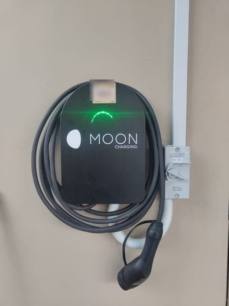 Moon Charging wallbox with a coiled grey cable beside its isolator and trunking