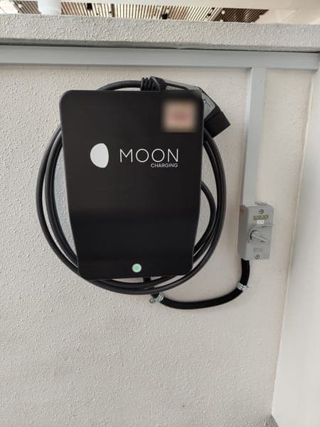 Moon Charging wallbox with a coiled cable below a porch roof