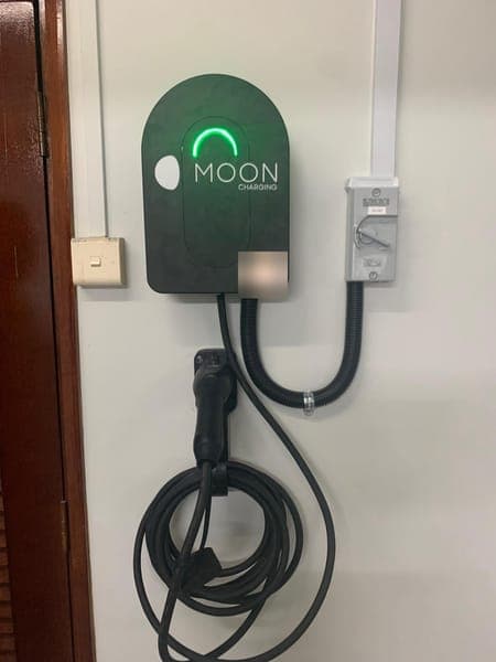 Moon Charging wallbox with a green light beside a timber door frame