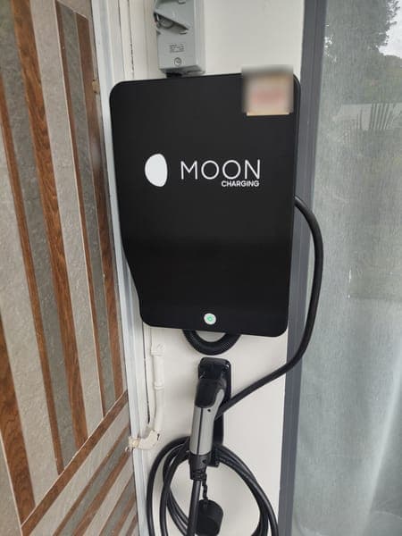 Moon Charging wallbox on a column beside timber-striped cladding