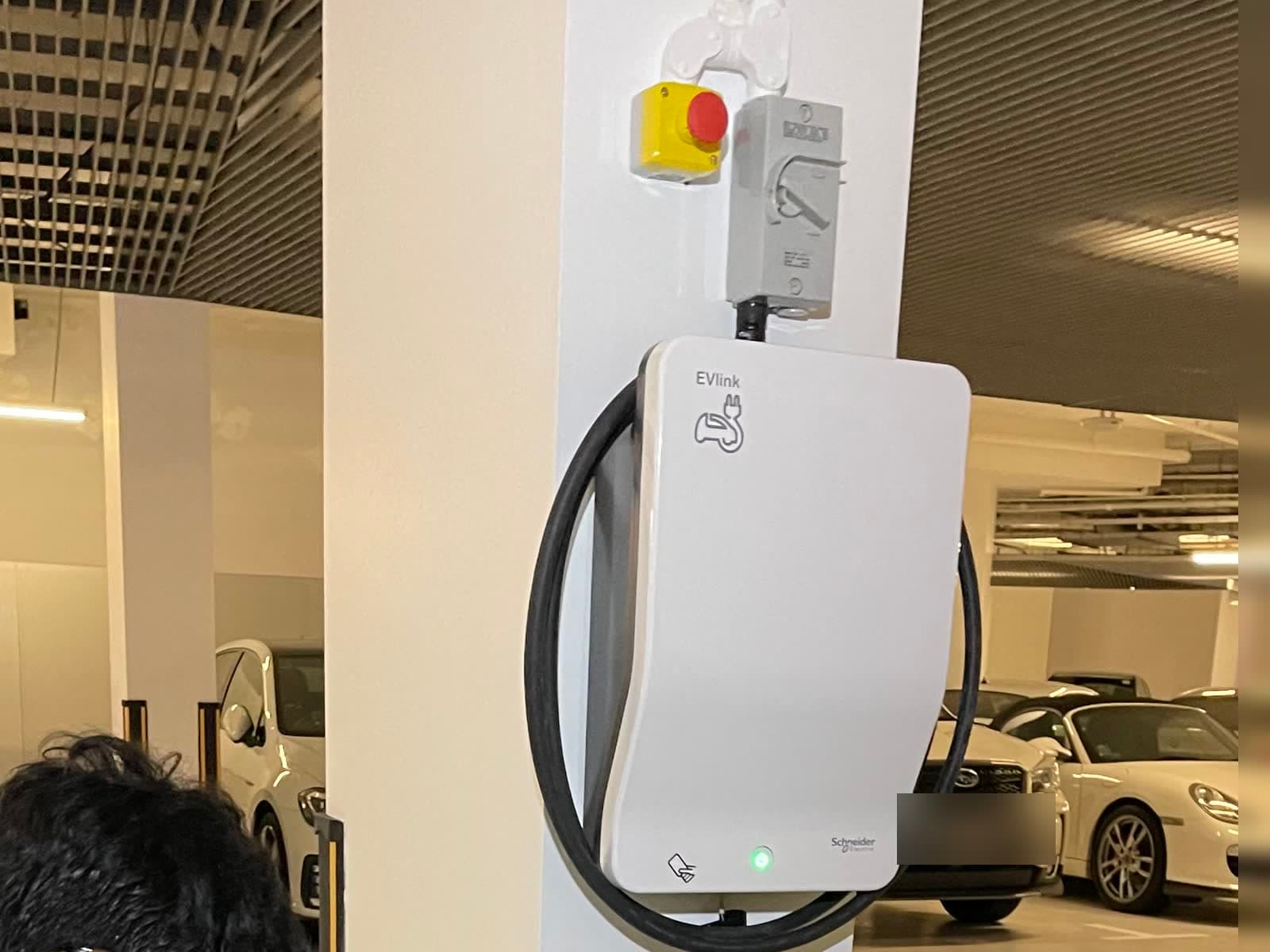 Shared EV charger with an emergency stop button and isolator switch above it in a condo car park at The Coast @ Sentosa Cove